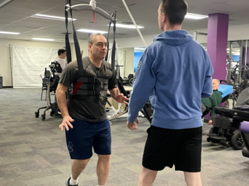 Patient performing gait training with Guldmann GH3+ ceiling hoist and Trainer module—enhancing mobility, resilience, and recovery from paralysis through dynamic weight relief technology.