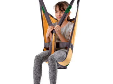 Guldmann Basic Basic Kids sling supporting a seated child beneath a ceiling-mounted hoist.