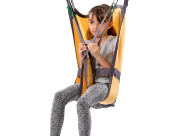Child seated in a Guldmann Basic High Kids sling suspended from a ceiling hoist for safe and supported lifting.
