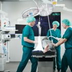 Nurses and surgeons work together to adjust the ceiling hoist system to suit the patient's needs.