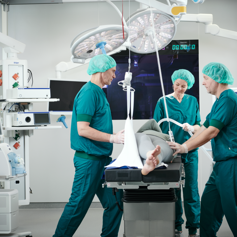 Nurses and surgeons work together to adjust the ceiling hoist system to suit the patient's needs.