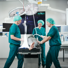 Las enfermeras y los cirujanos trabajan juntos para ajustar el sistema de grúas de techo según las necesidades del paciente.