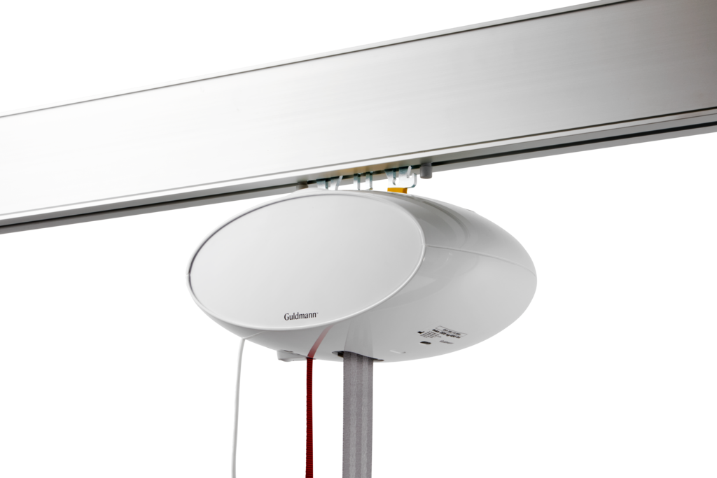 GH1 plafondliftmodule met witte afdekkap, gemonteerd op een rails voor tilondersteuning.