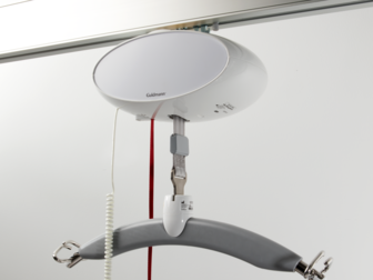 GH1 ceiling hoist lifting module installed on a rail system in a care environment.