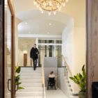 Rolstoelgebruiker gaat omhoog op Stepless SLP model C platformlift naast trap in T-House