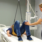 Patient performing a pelvic lift exercise using Guldmann Elastic Line for rehabilitation.