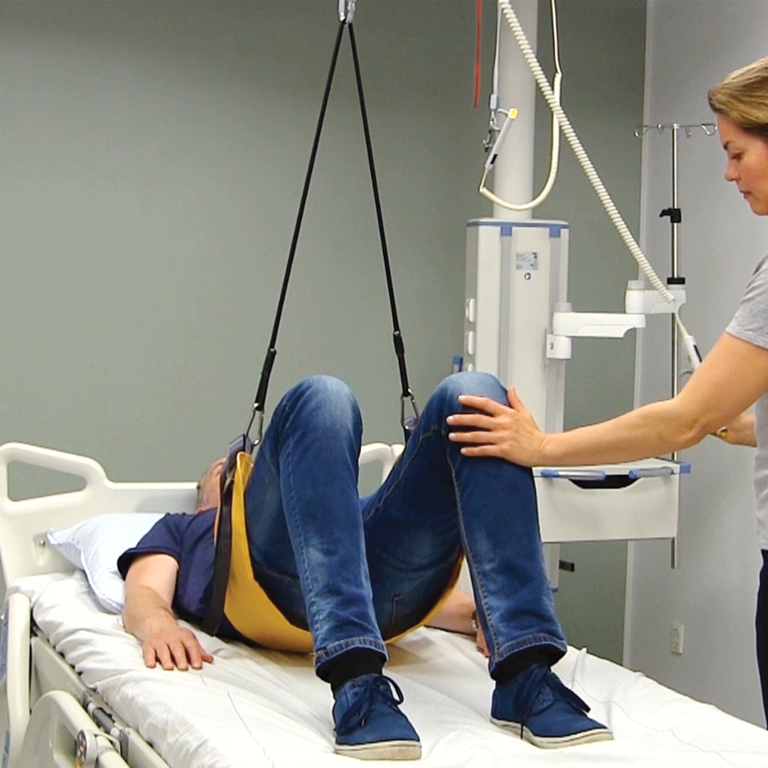 Patient performing a pelvic lift exercise using Guldmann Elastic Line for rehabilitation.